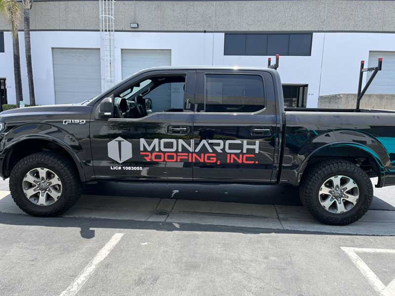 Side view of Monarch Roofing's pickup truck with their logo on the driver side door